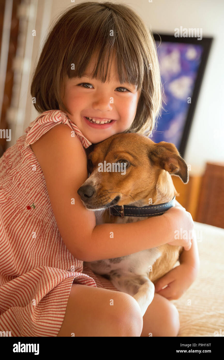 Il Toddler girl abbracciando il suo cane a casa Foto Stock