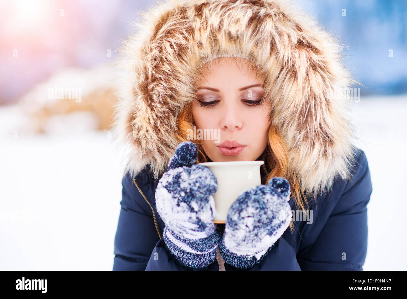 Attraente giovane donna fuori nella neve con una tazza di caffè Foto Stock