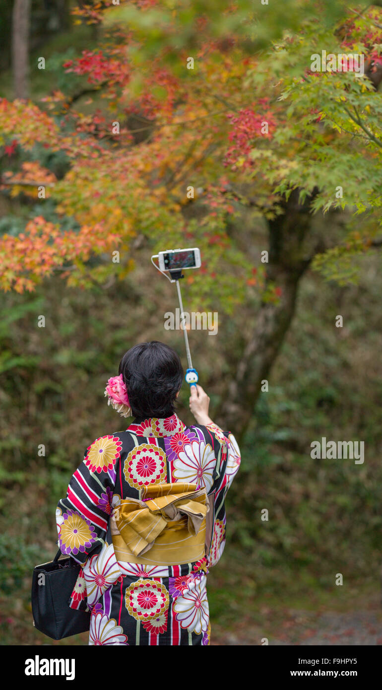 KIMONO giapponese ragazza placcati tenendo SELFIE NEL PARCO, BYODOIN TEMPLE (1053) UJI, GIAPPONE Foto Stock
