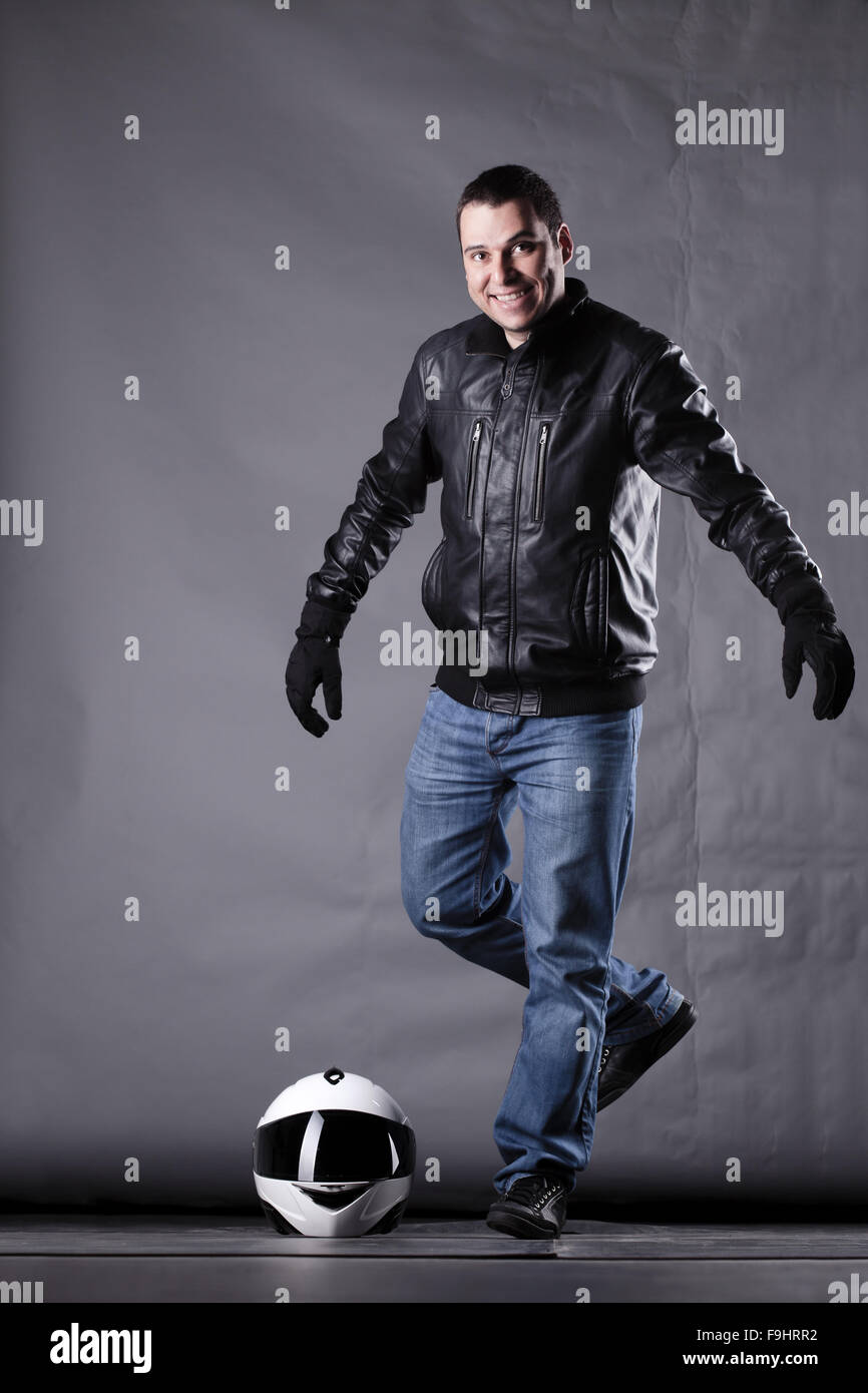 Automobilista con un casco, giacca di pelle e jeans, su sfondo grunge con illuminazione difficili Foto Stock Automobilista con un casco, giacca di pelle e jeans, su sfondo grunge con illuminazione difficili Foto Stock