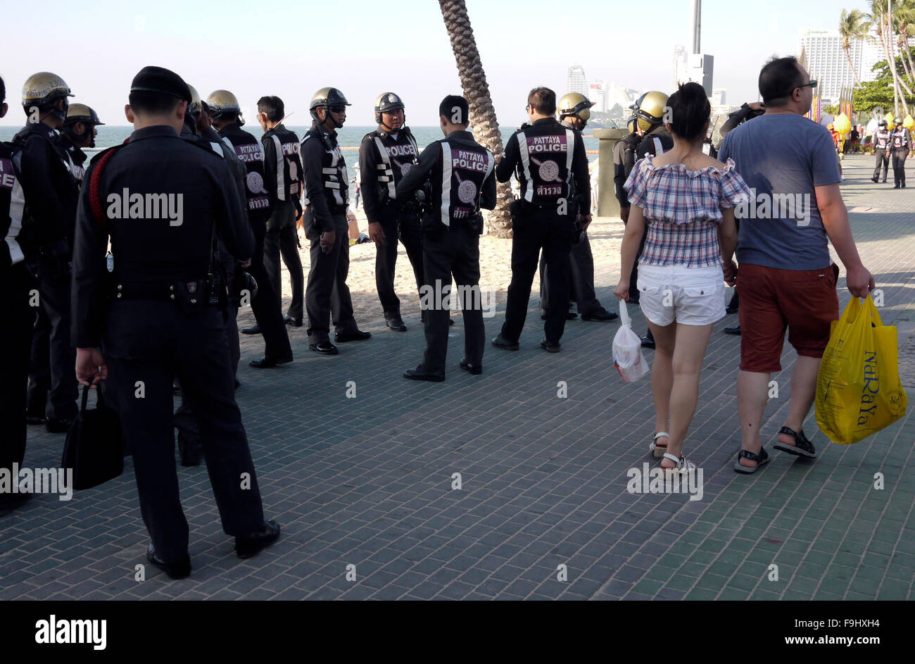 Due turisti a piedi davanti a un gruppo di poliziotti locali sulla strada della spiaggia di Pattaya Thailandia Foto Stock