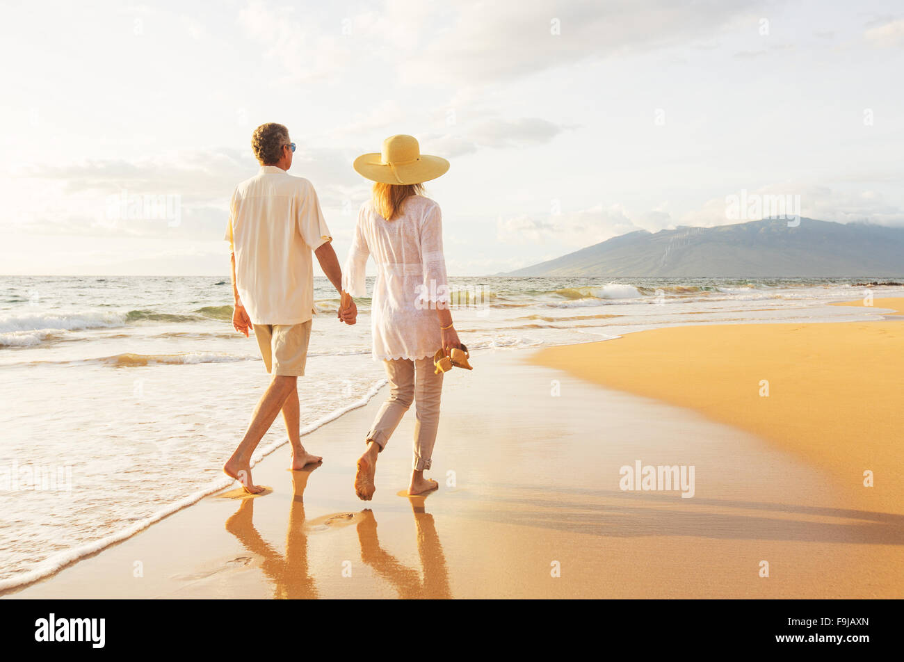 Romantica felice coppia di mezza età godendo bel tramonto a piedi sulla spiaggia. Travel Vacation pensionamento il concetto di stile di vita Foto Stock