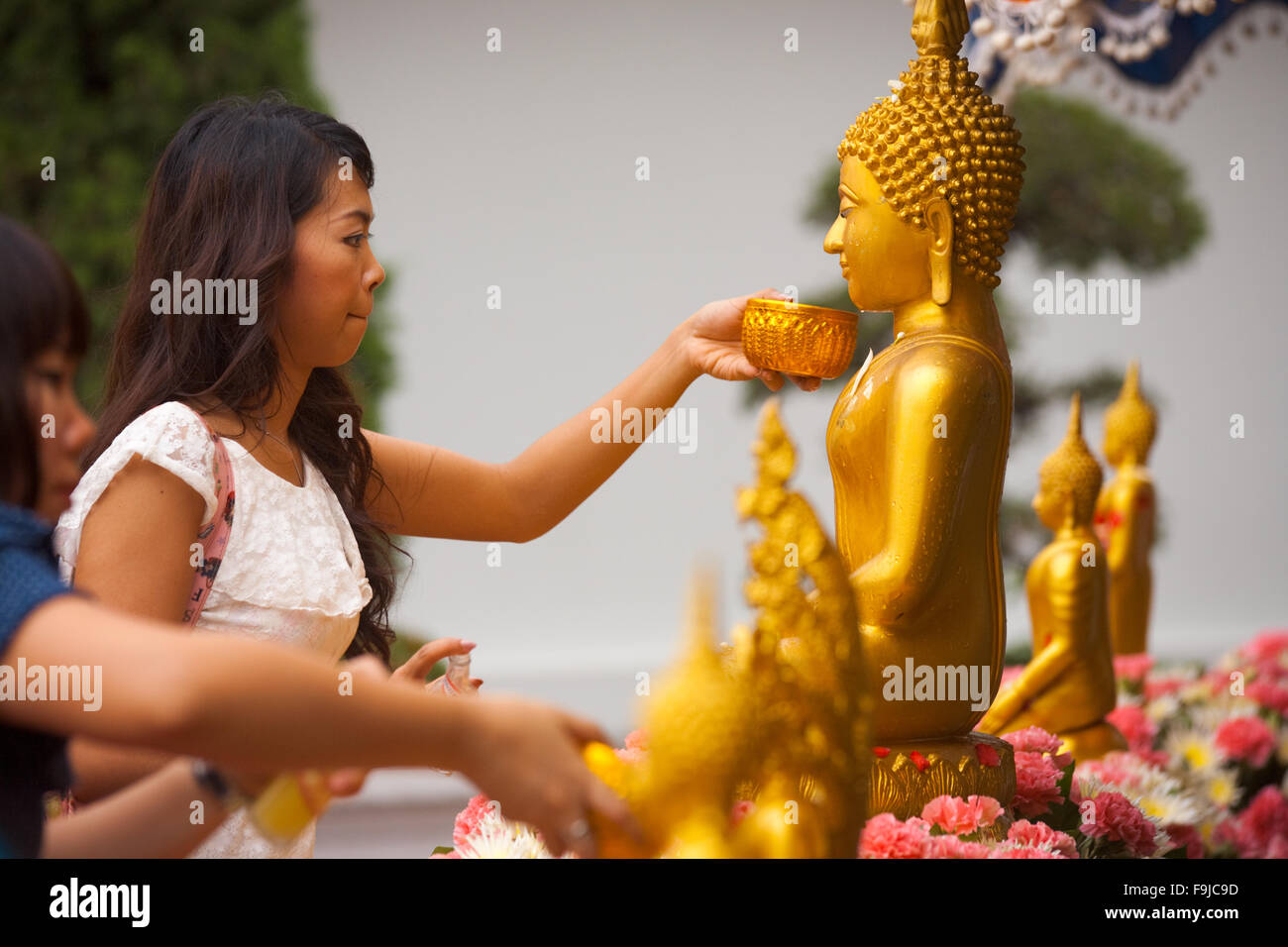 Buddista donna Thai pulizia, balneazione statua del Buddha di guadagnare il merito, un rituale annuale per la vacanza di Songkran o Thai Anno Nuovo Foto Stock