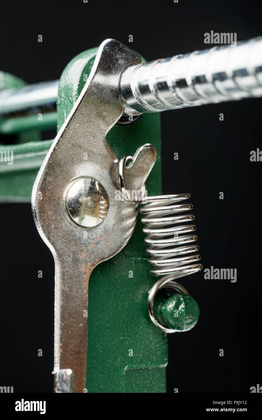 Macro dettaglio di una molla metallica su una macchina di taglio, su sfondo nero Foto Stock