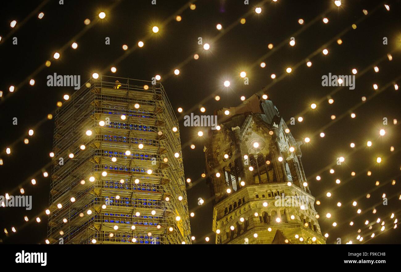 Berlino, Germania. Xvi Dec, 2015. Una stringa di luci al mercatino di Natale sulla Breitscheidplatz è illuminato nella parte anteriore del Kaiser Wilhlem Memorial Church di Berlino, Germania, 16 dicembre 2015. L'edificio originale fu costruito da 1891-95 a seguito di piani da Franz Schwechten. Dopo la Seconda Guerra Mondiale le rovine (R) erano protetti come un anti-War Memorial. Una nuova torre fu eretta a seguito di piani da architetto Egon Eiermann. Foto: PAOLO ZINKEN/dpa/Alamy Live News Foto Stock