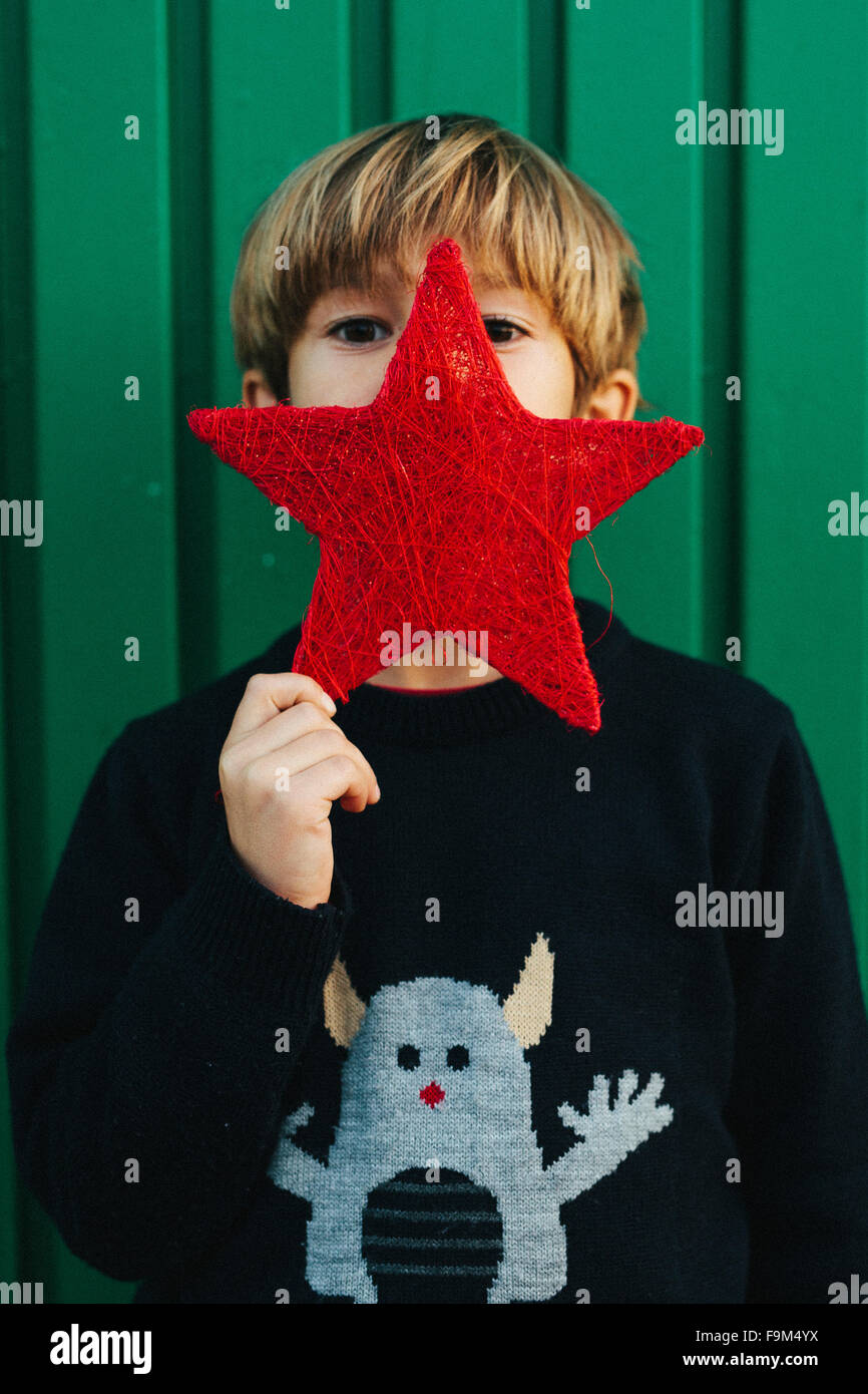 6 anni vecchio ragazzo tenendo una stella rossa nella parte anteriore del suo volto Foto Stock
