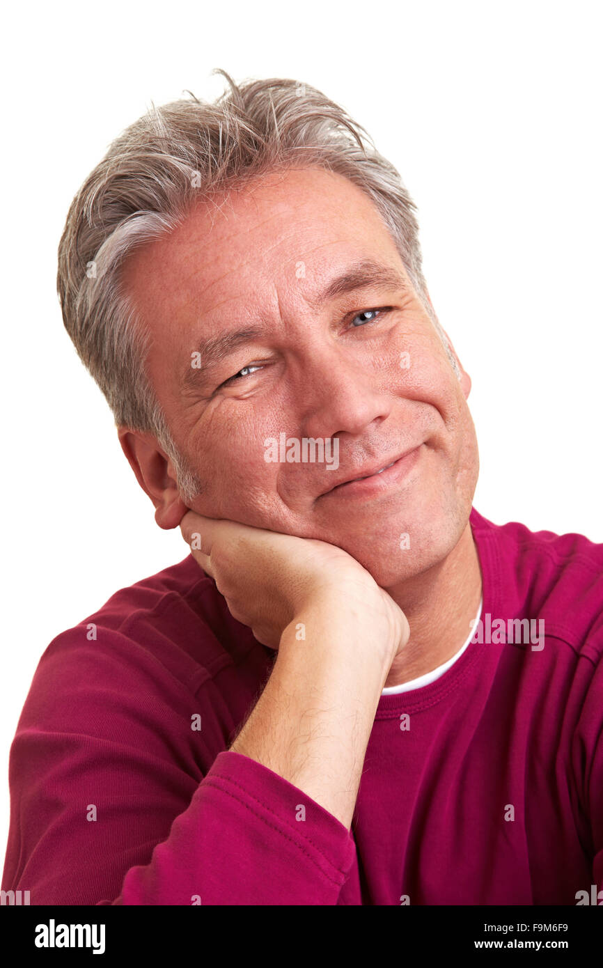 Sorridente uomo anziano mettendo la mano al suo mento Foto Stock