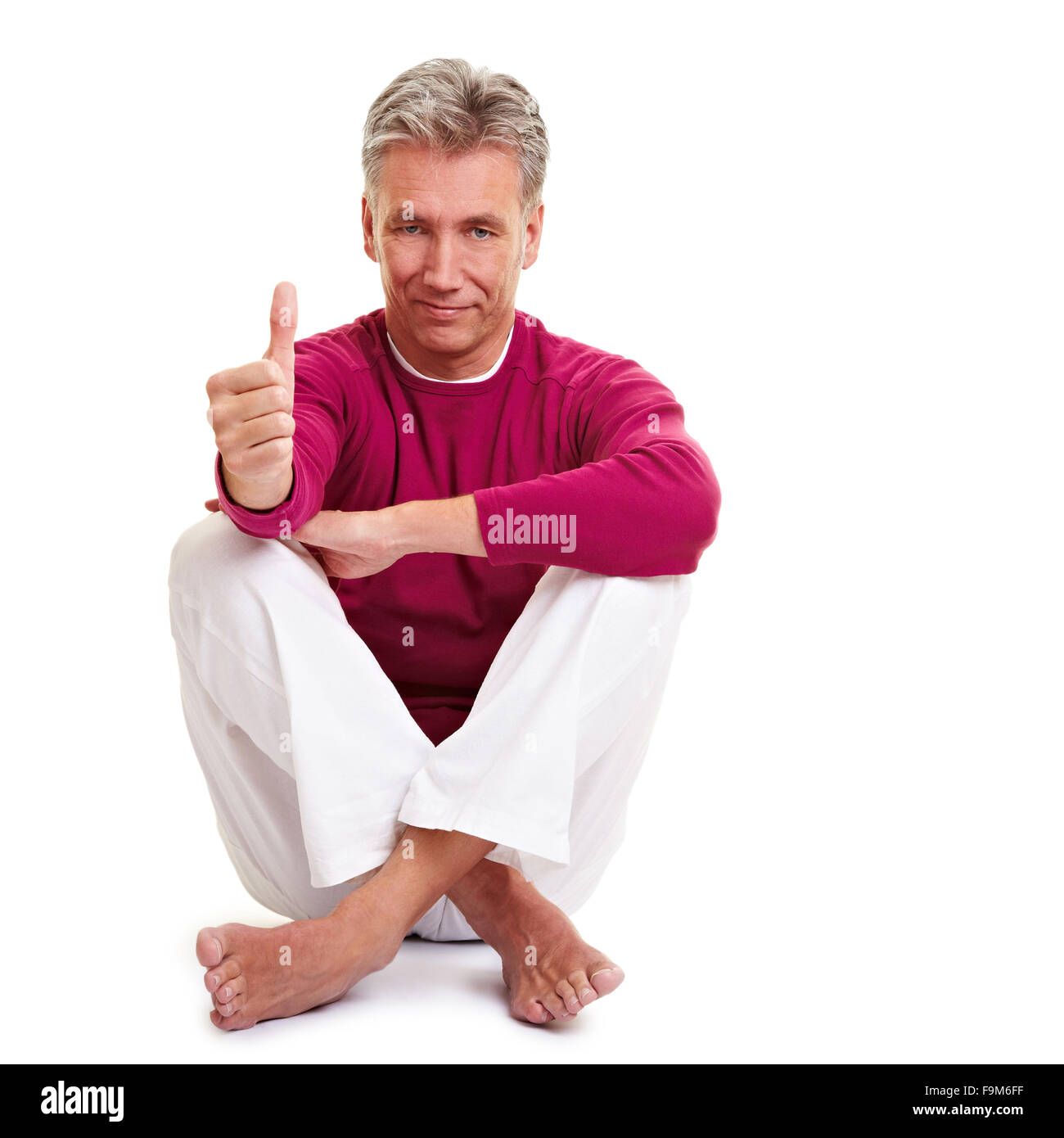 Rilassata insegnante di yoga tenendo il suo pollice in alto Foto Stock