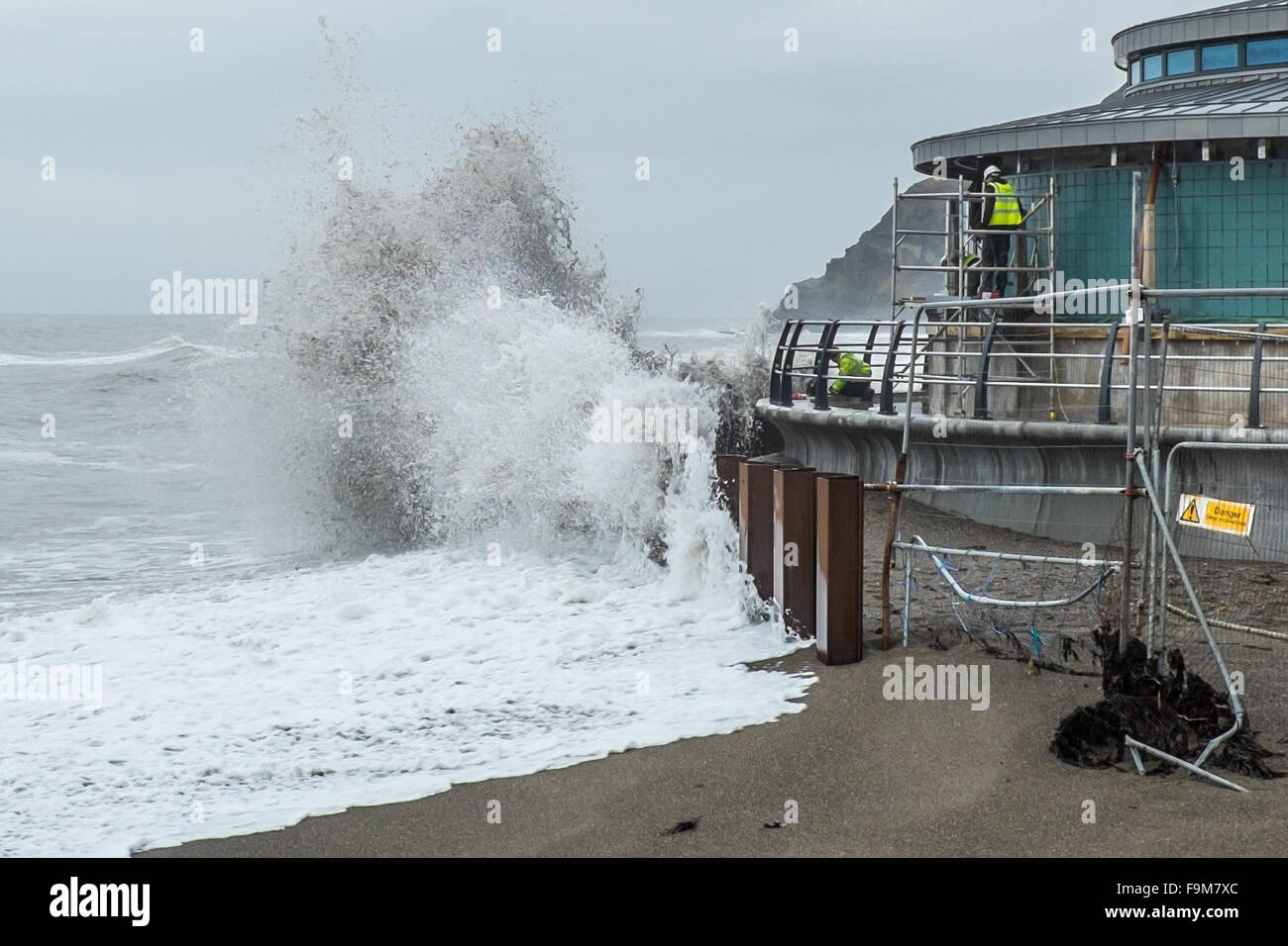 Aberystwyth, Wales, Regno Unito. Il 17 dicembre 2015. Nonostante le onde che si infrangono intorno a loro, operai continuare a lavorare nella speranza di incontrare il Natale la scadenza per il completamento di Aberystwyth è di nuovo mare bandstand Credito: Alan Hale/Alamy Live News Foto Stock