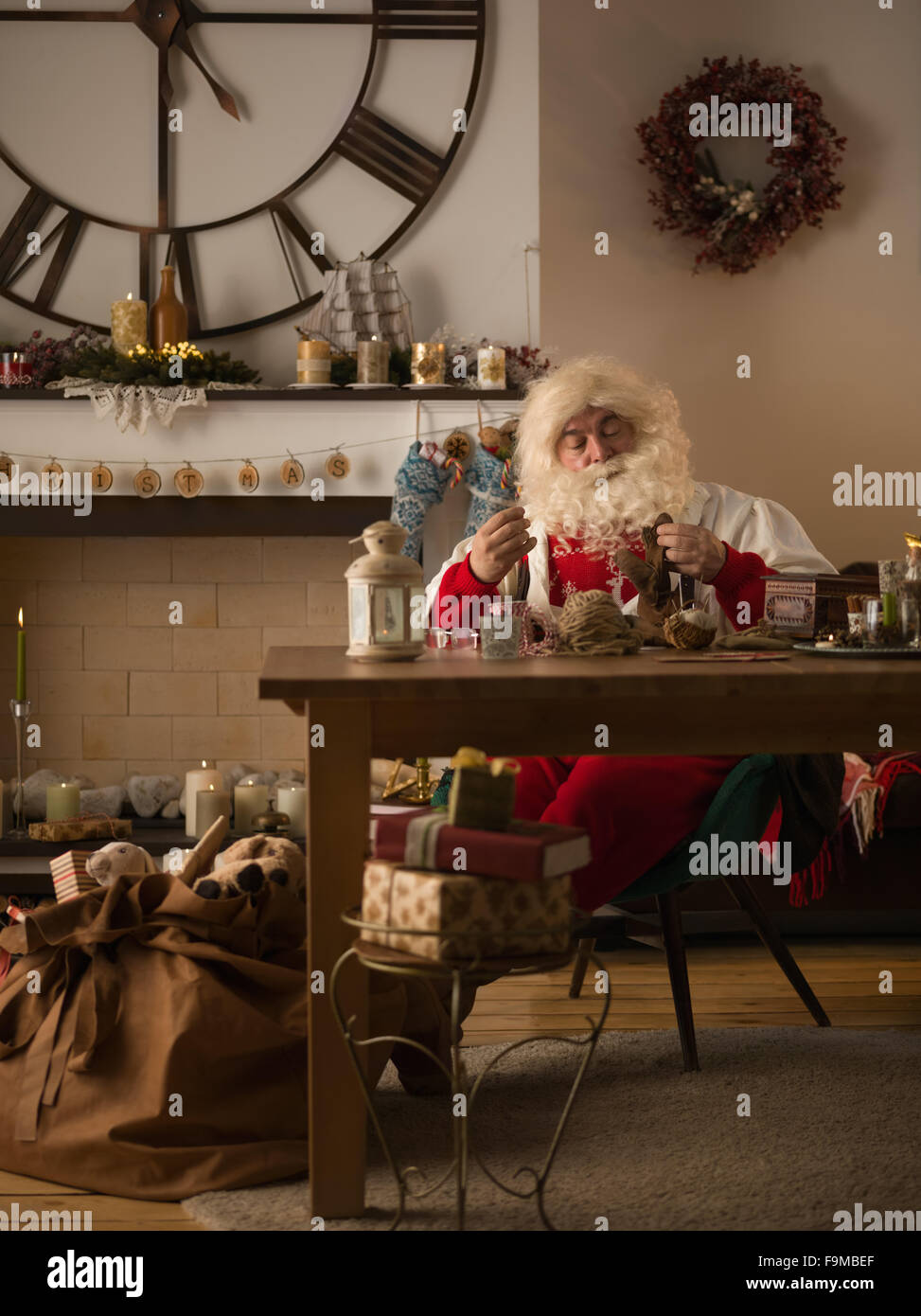 Babbo Natale a lavorare a casa. Riparare i guanti Foto Stock