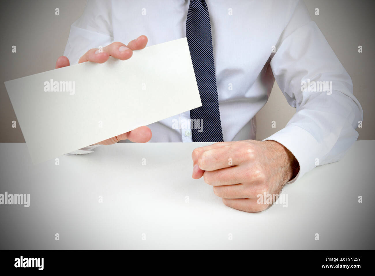 Un uomo vestito in camicia e cravatta con in mano una carta Foto Stock