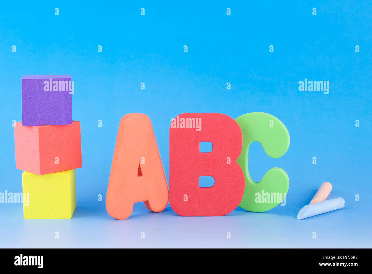 ABC lettere e colorati di cubetti di schiuma e gessi su sfondo blu Foto Stock