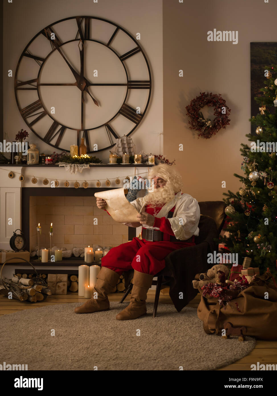 Babbo Natale lettura Wishlist vicino albero di Natale a casa Foto Stock