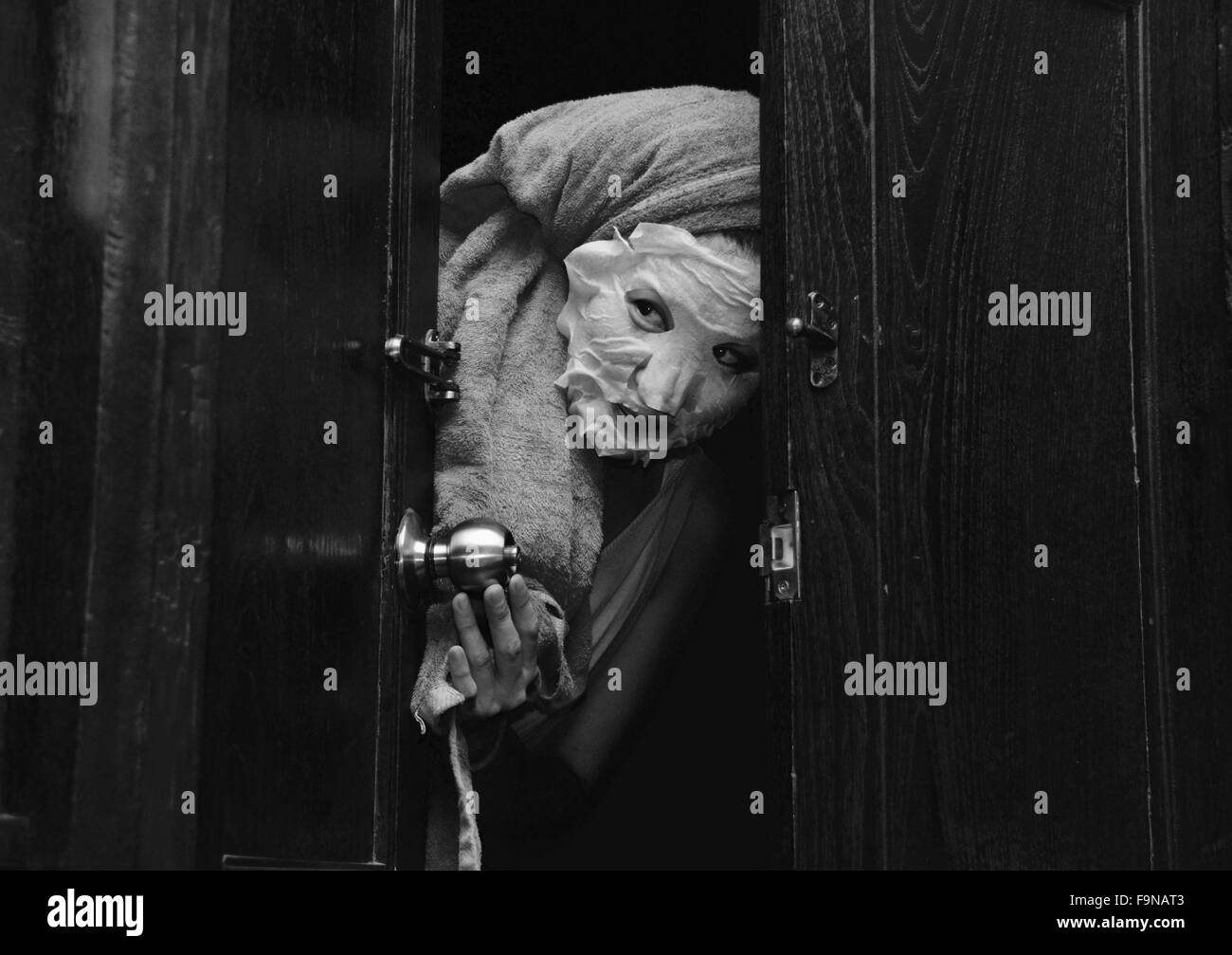 Donna Giapponese cercando gettò una porta che indossa una maschera di pulizia Foto Stock