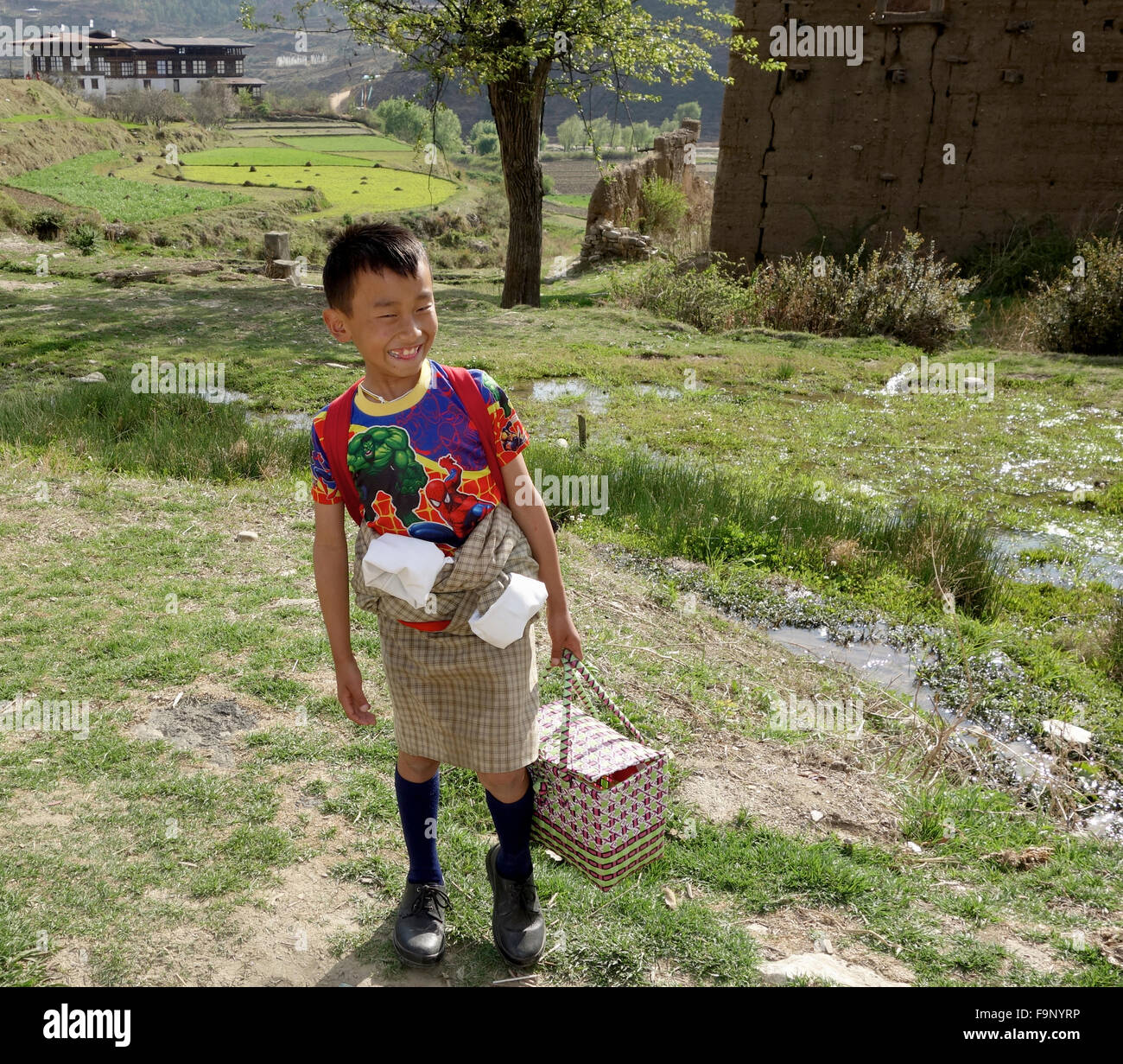 Un giovane ragazzo scuola in Bhutan con un pranzo al sacco e sacchetto di scuola Foto Stock