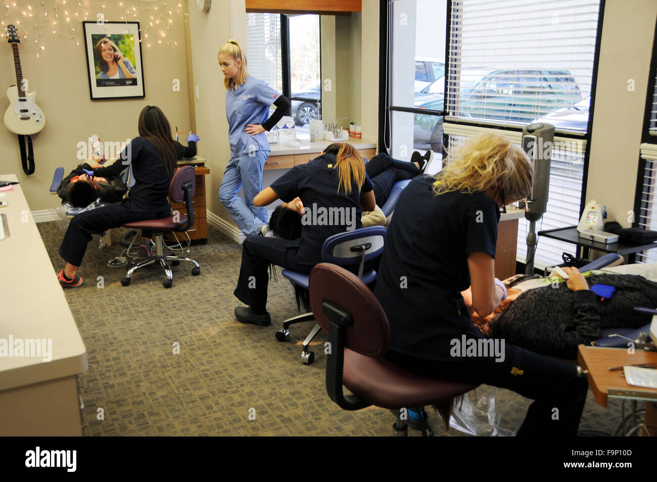 Un ortodontista è un dentista specializzato di raddrizzare i denti storti. Diversi assistenti regolando le bretelle di pazienti. Foto Stock