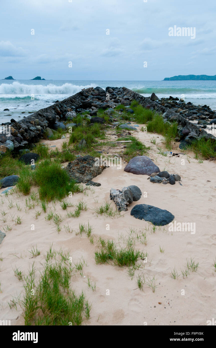 Il percorso stretto riempito con grosse pietre l'oceano di fronte a una spiaggia Foto Stock