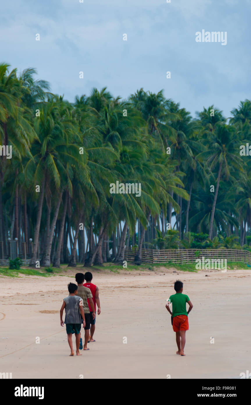 Un gruppo di ragazzi a piedi la spiaggia di sabbia di fronte o alberi di palma Foto Stock Un gruppo di ragazzi a piedi la spiaggia di sabbia di fronte o alberi di palma Foto Stock