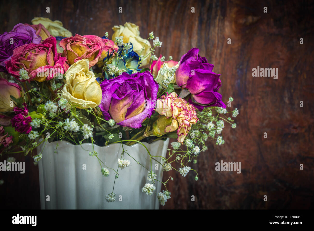 Vintage conservati colorati Rose sul tono scuro dello sfondo in legno Foto Stock