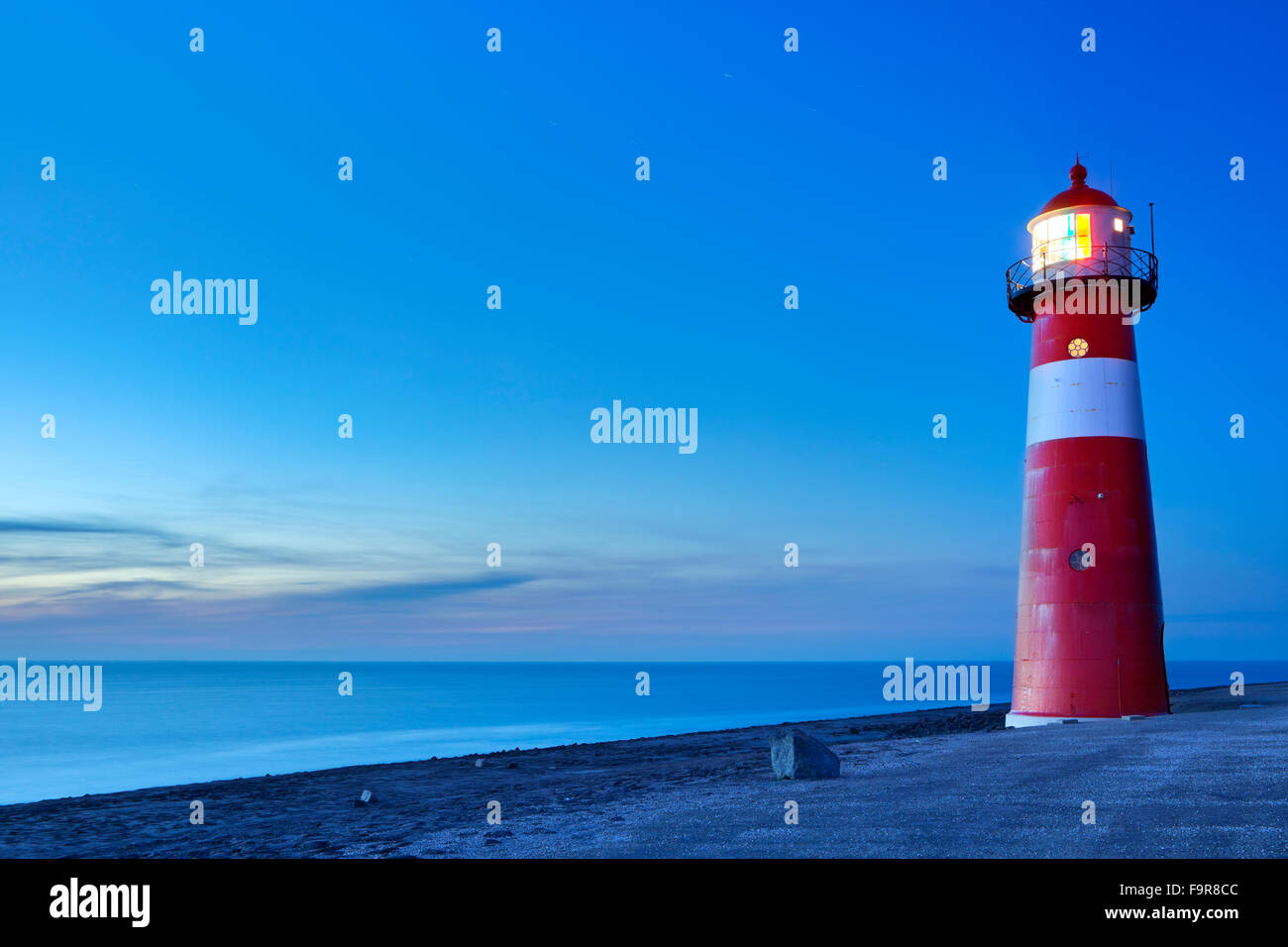 Un rosso e bianco faro di mare. Fotografato al tramonto vicino a Westkapelle in Zeeland, Paesi Bassi. Foto Stock