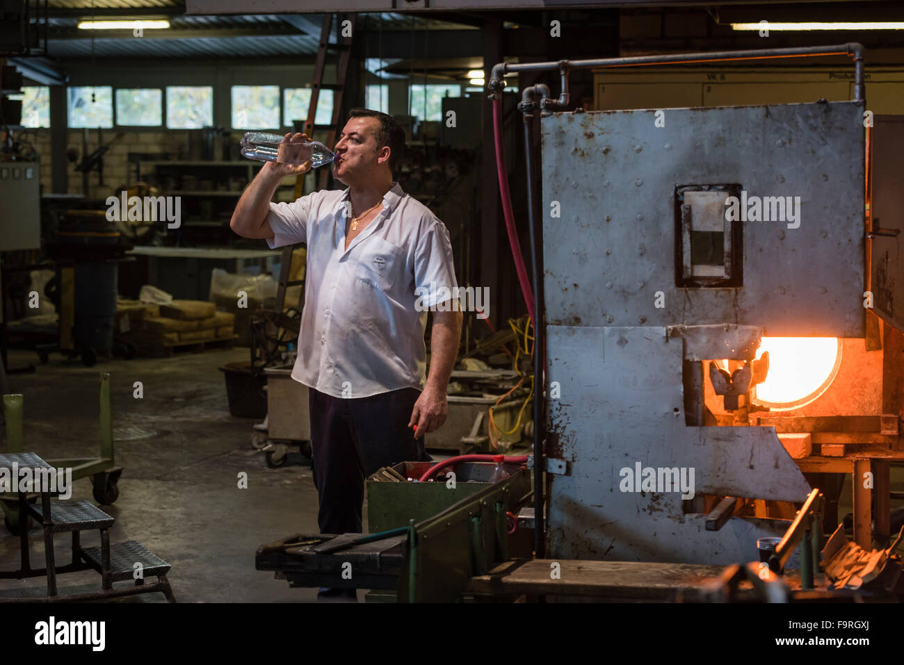 Esaurito dal calore del forno per vetro, una glassblower prende una pausa alla fabbricazione del vetro in Hergiswil, Svizzera. Foto Stock