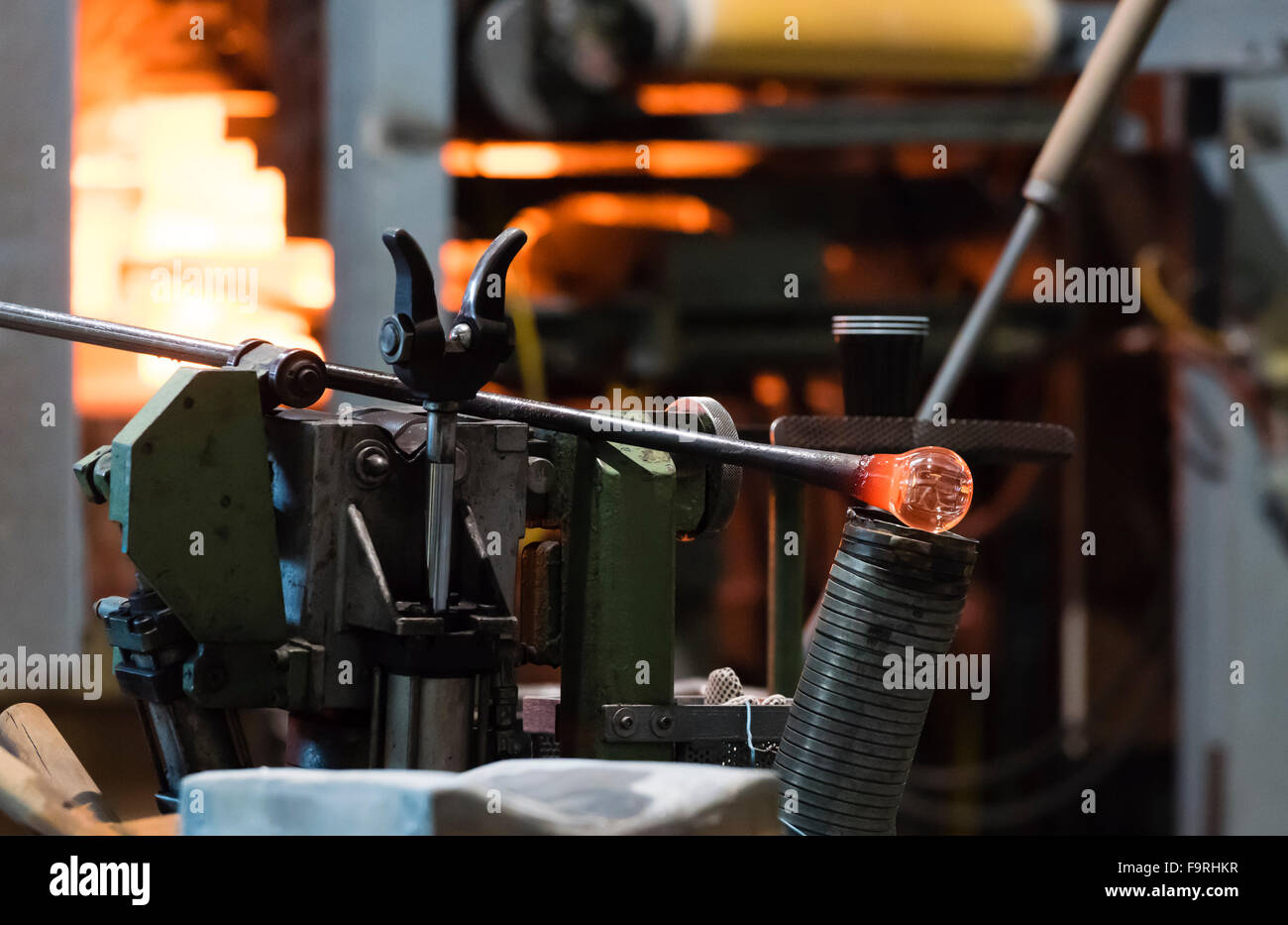 Un pezzo di red hot il vetro fuso viene raffreddato prima di un ulteriore trattamento in una fabbrica glassblowing/forno. Foto Stock
