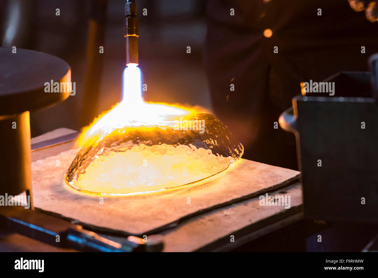 Un glassblower con una torcia soffiante è di aggiungere il tocco finale a una ciotola di vetro presso la fabbrica di vetro di Hergiswil, Svizzera. Foto Stock