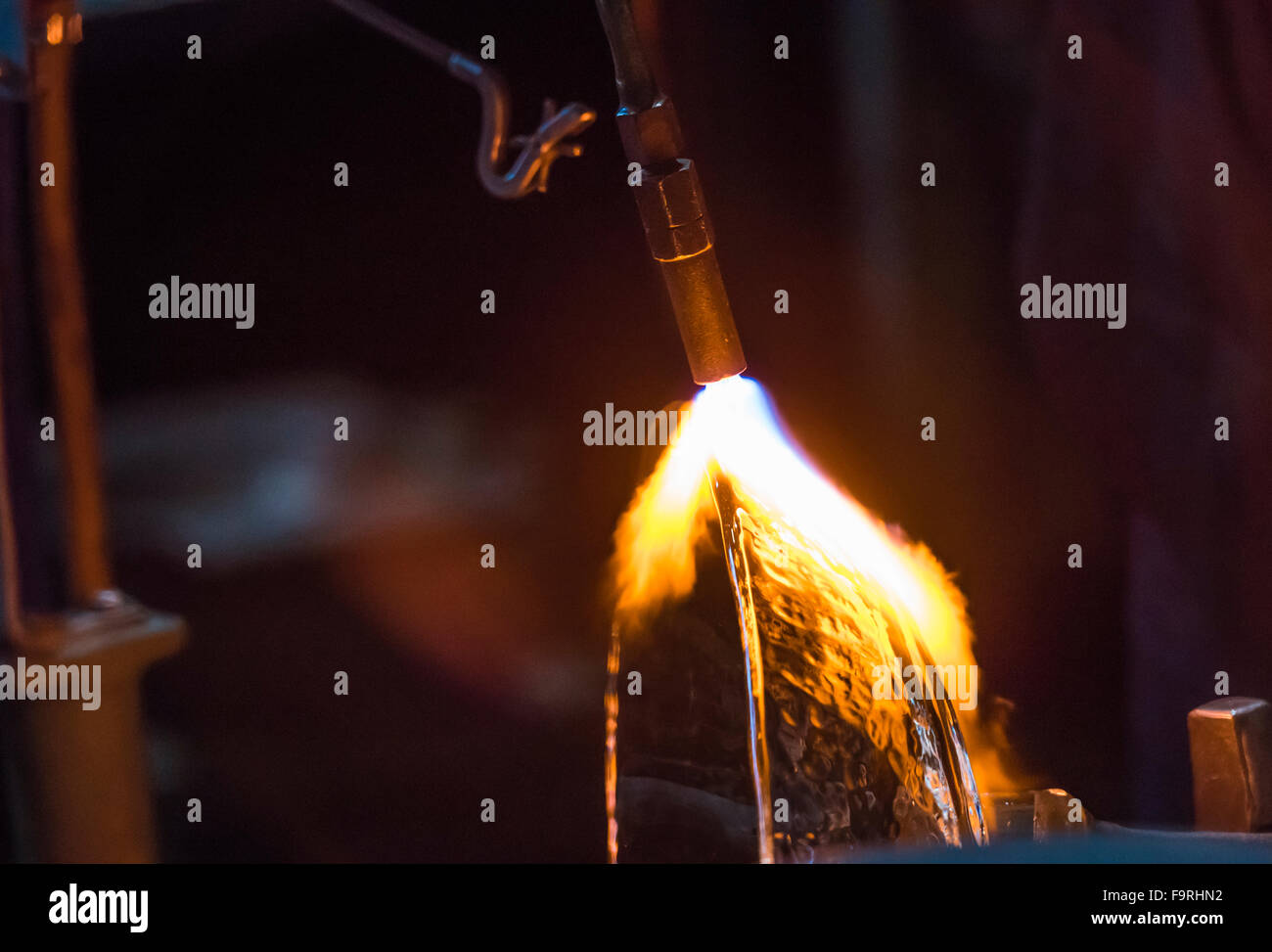 Un glassblower con una torcia soffiante è di aggiungere il tocco finale a una ciotola di vetro presso la fabbrica di vetro di Hergiswil, Svizzera. Foto Stock