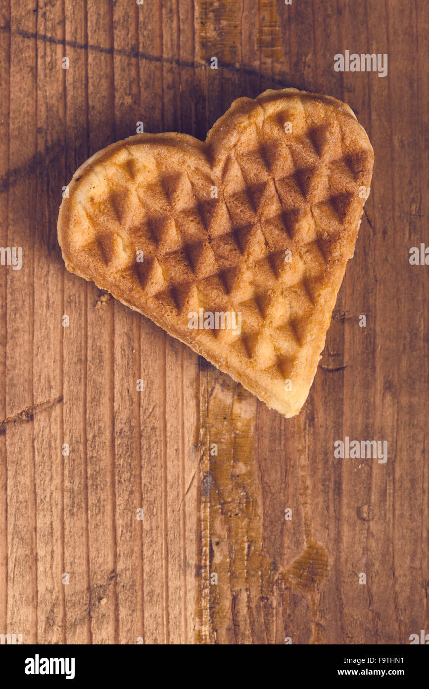A forma di cuore i waffle fatti in casa sulla scrivania in legno, dai toni retrò, vista dall'alto. Foto Stock