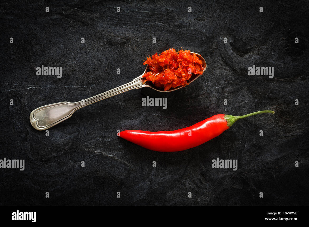 Cucchiaio di fatti in casa pasta di peperoncino e peperoncino pod sulla massa nero Foto Stock