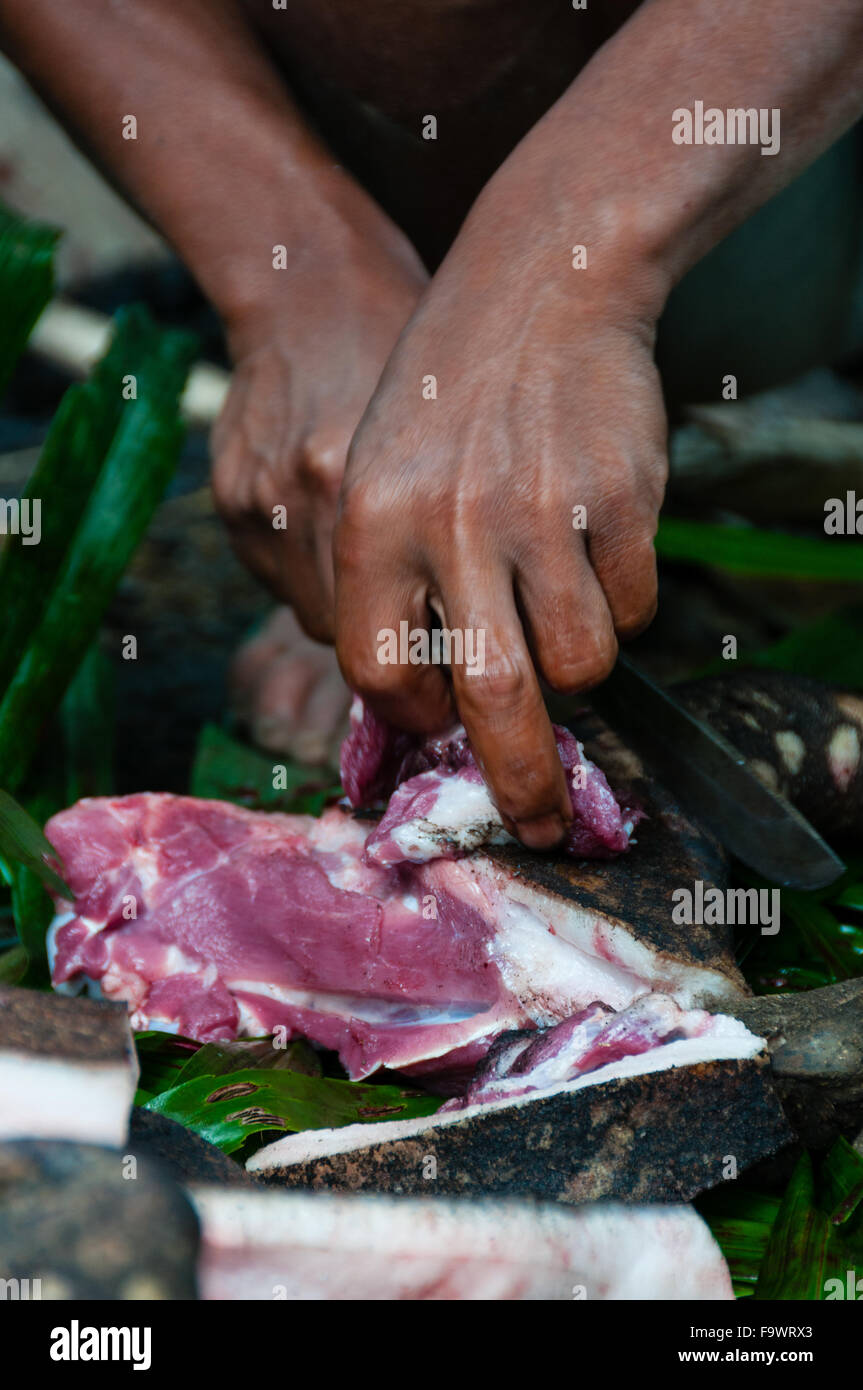 Closeup mani rosso di taglio di carne di maiale a pezzetti con un coltello Foto Stock