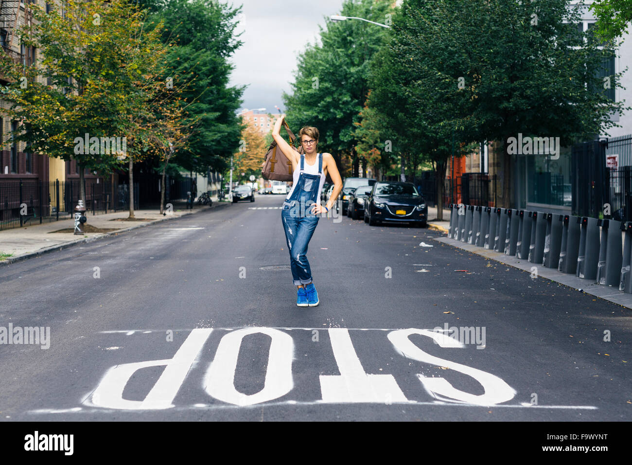 Stati Uniti d'America, New York City, Williamsburg, donna che indossa jeans salopette da posa su strada Foto Stock