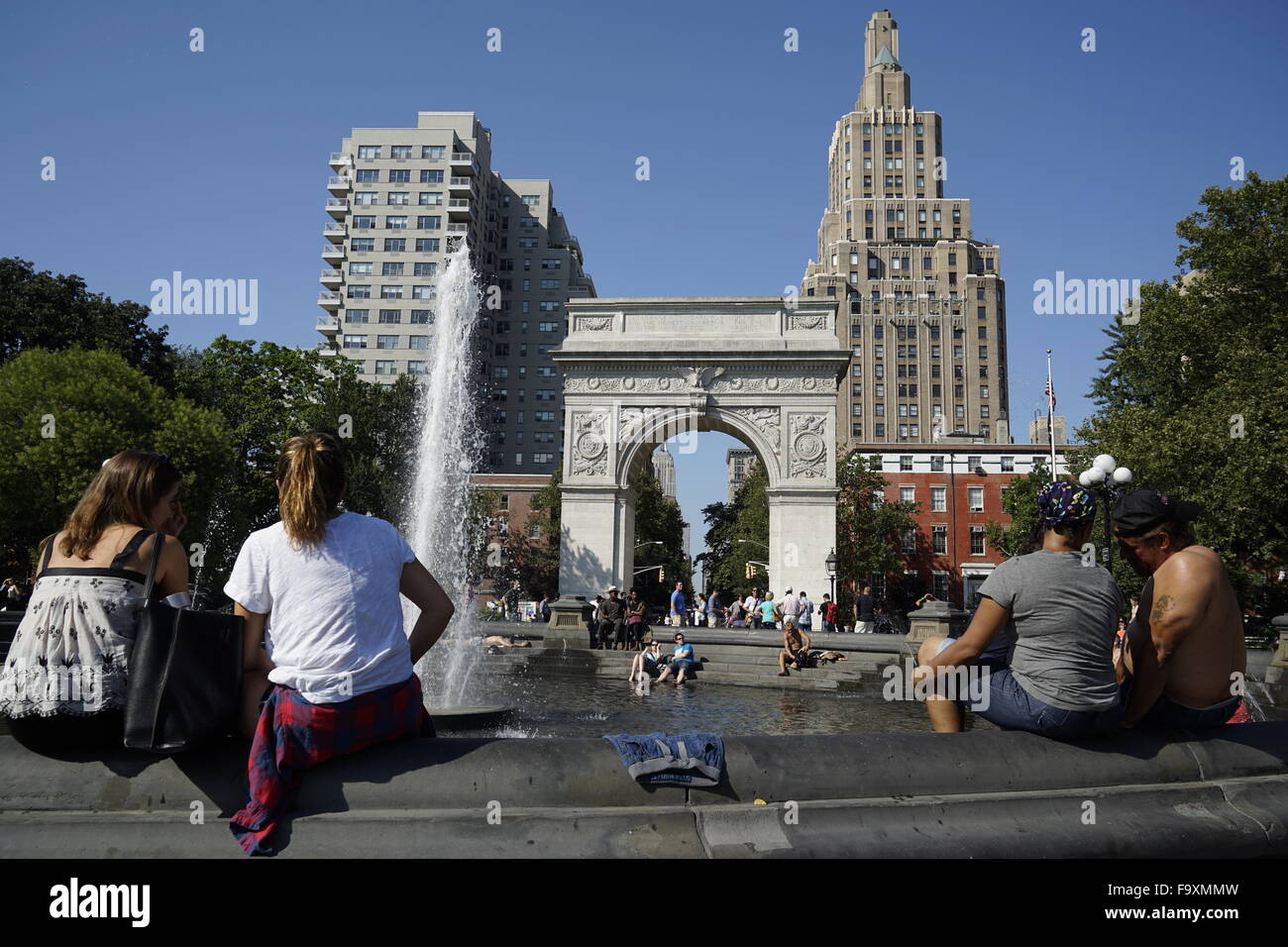 Visitatori relax presso la fontana centrale a Washington Square Park con Washington Square Arch in background, New York City Foto Stock