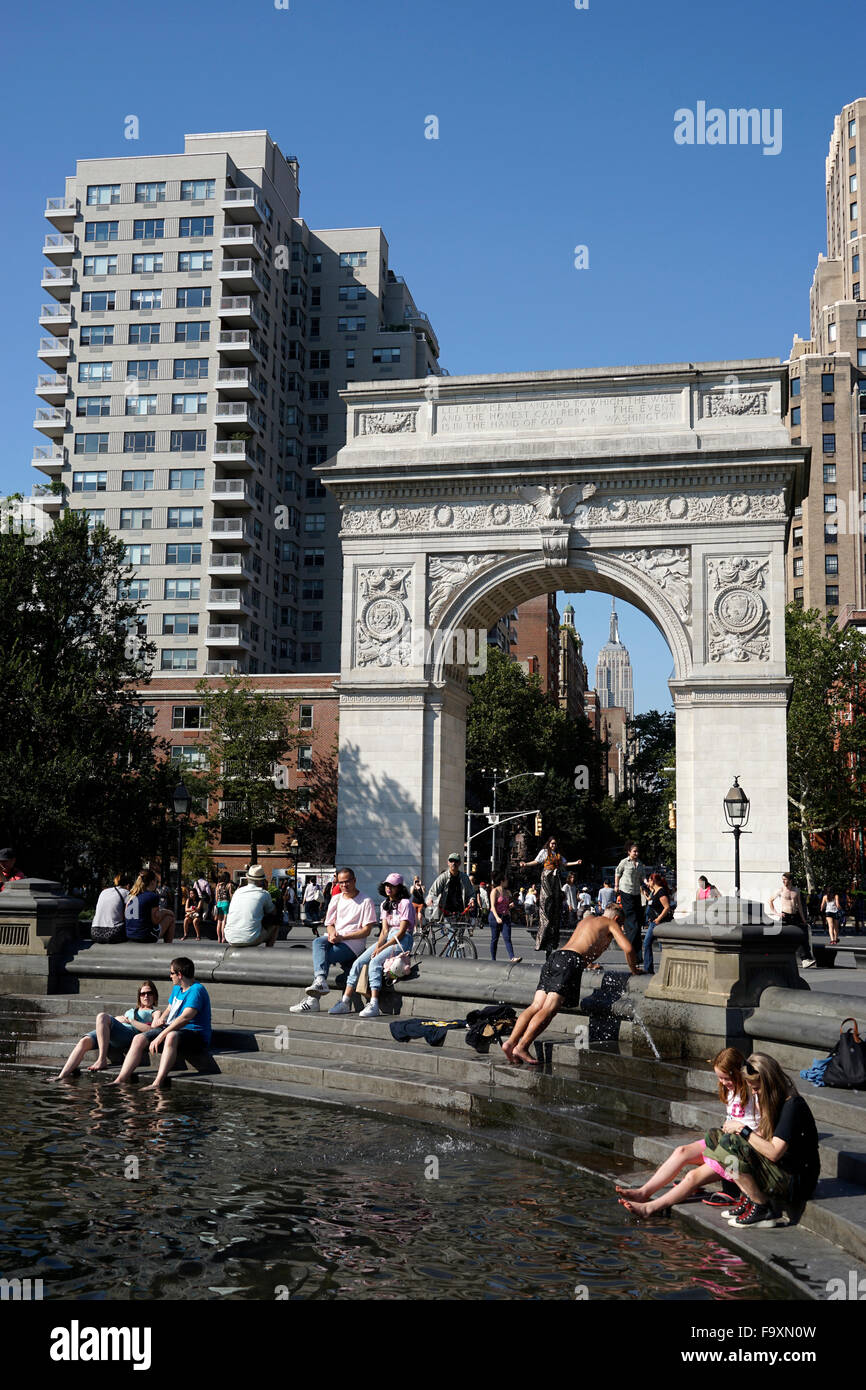Visitatori relax presso la fontana centrale a Washington Square Park con Washington Square Arch in background, New York City Foto Stock