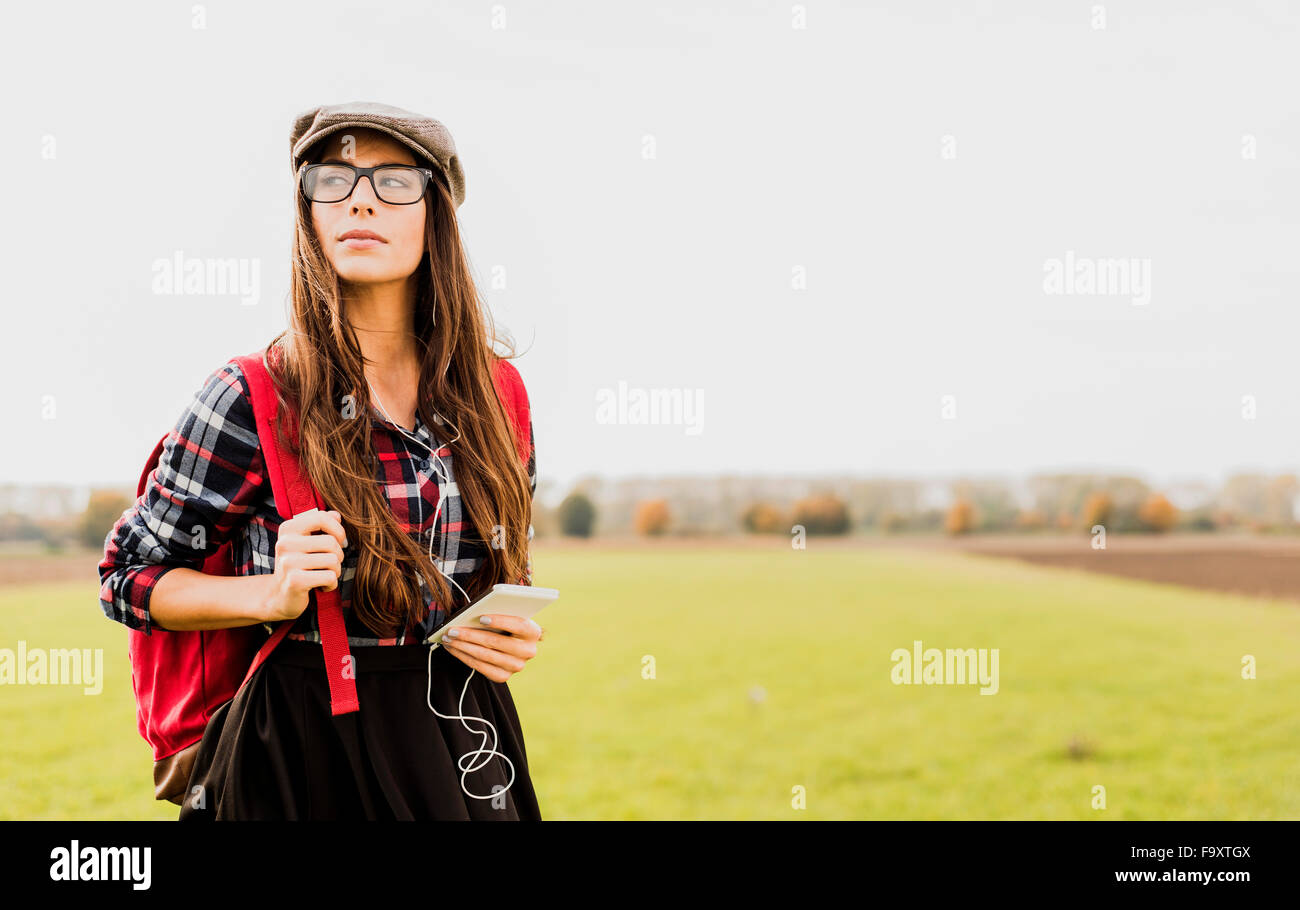 Giovane donna con zaino e dispositivo portatile in campagna Foto Stock