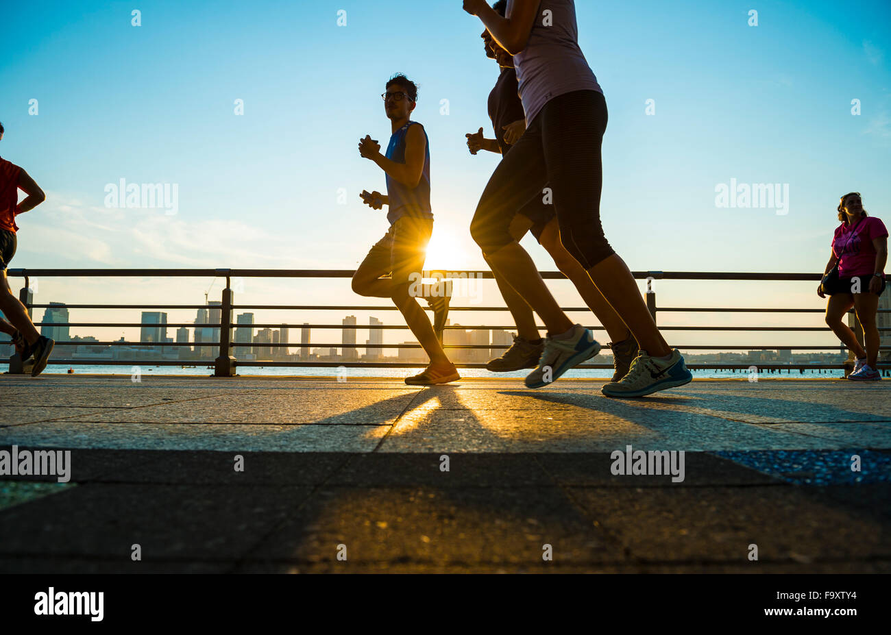 La città di NEW YORK, Stati Uniti d'America - Agosto 15, 2015: sagome di uomini eseguire al tramonto sul fiume Hudson Boardwalk. Foto Stock