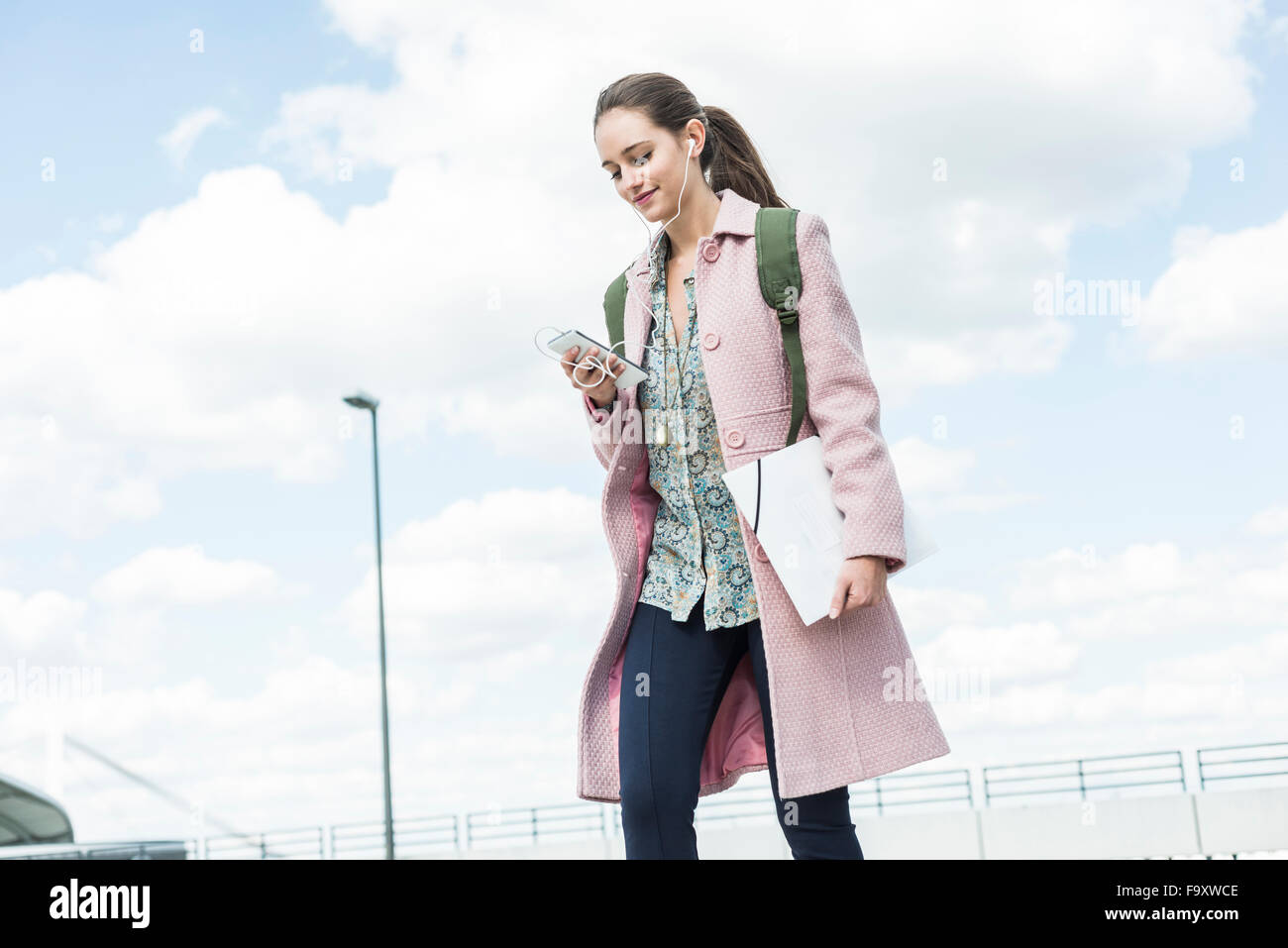 Giovane donna con gli auricolari e il telefono cellulare sul go Foto Stock