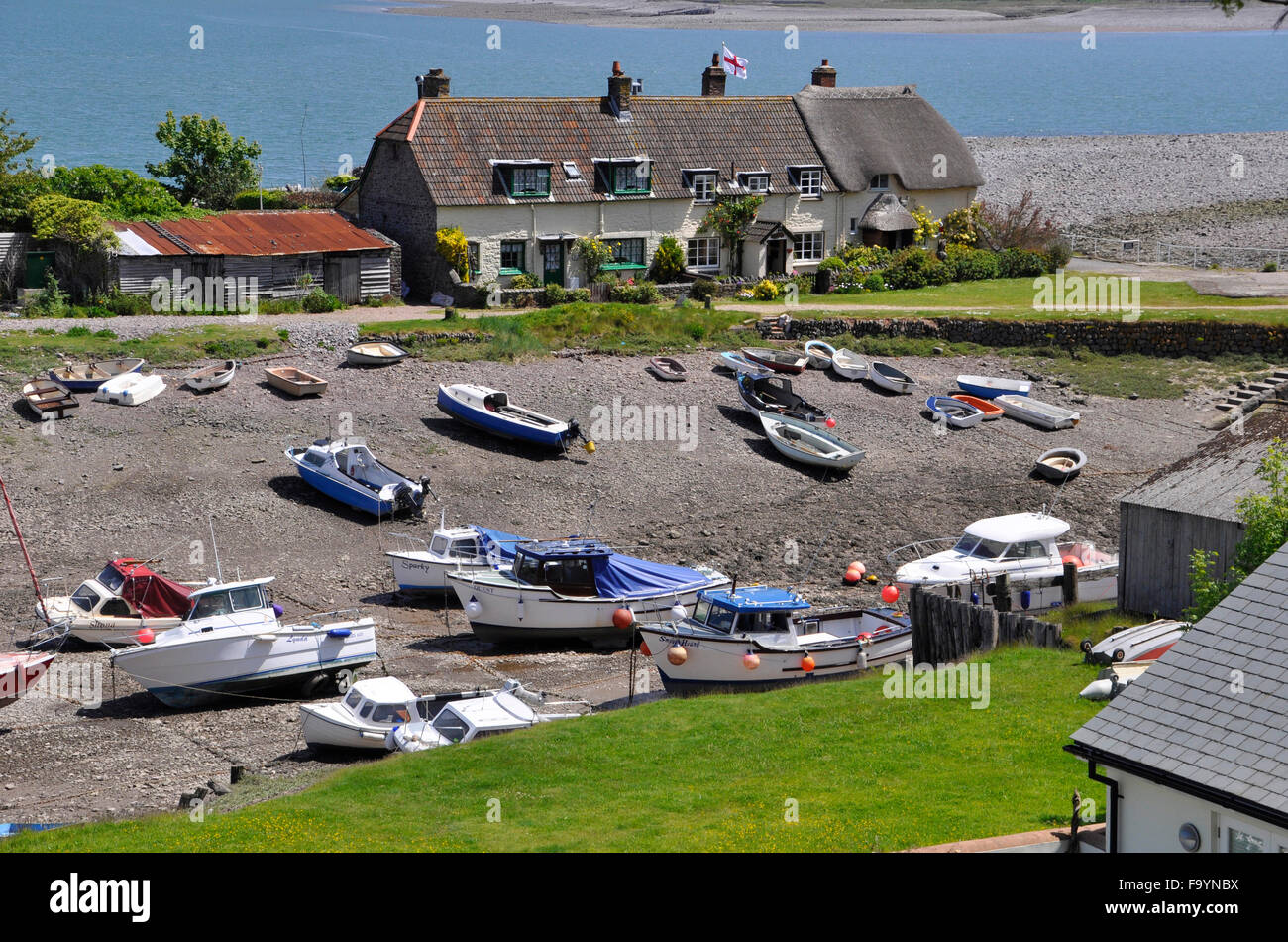 Vista di cottage e barche con tetto di paglia a Porlock Weir, con marea out, Somerset, Regno Unito Foto Stock