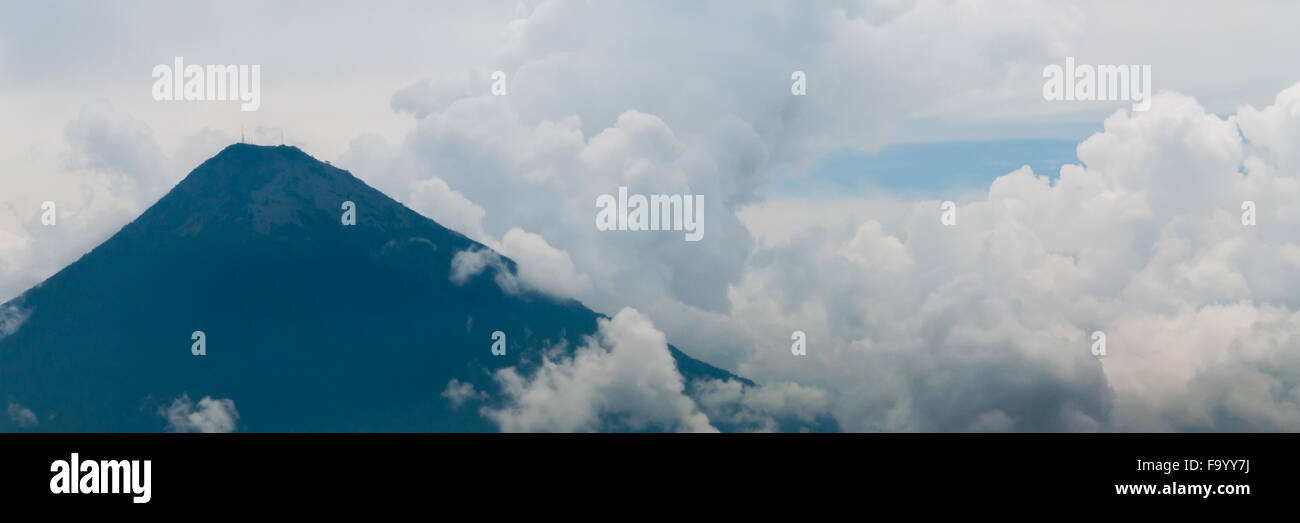 Grande cima del vulcano circondato dalla nebbia e dense nubi su campo verde Foto Stock Grande cima del vulcano circondato dalla nebbia e dense nubi su campo verde Foto Stock
