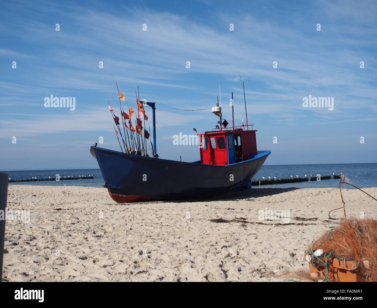 Blu rosso barca da pesca con bandiera a costa del mare Foto Stock