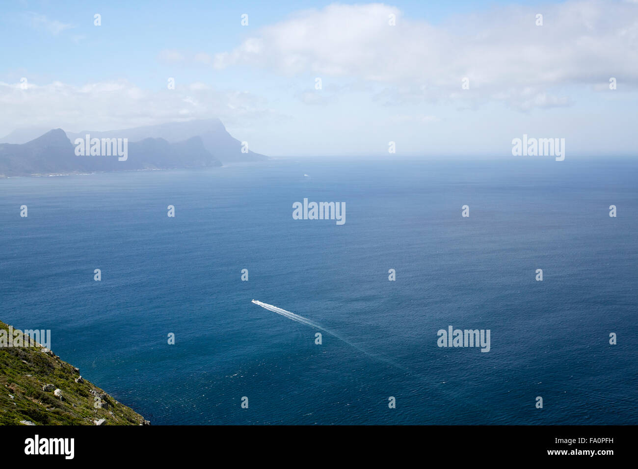 Una barca a motore in Oceano Atlantico vicino a Cape Point in Sud Africa, con le montagne sullo sfondo Foto Stock