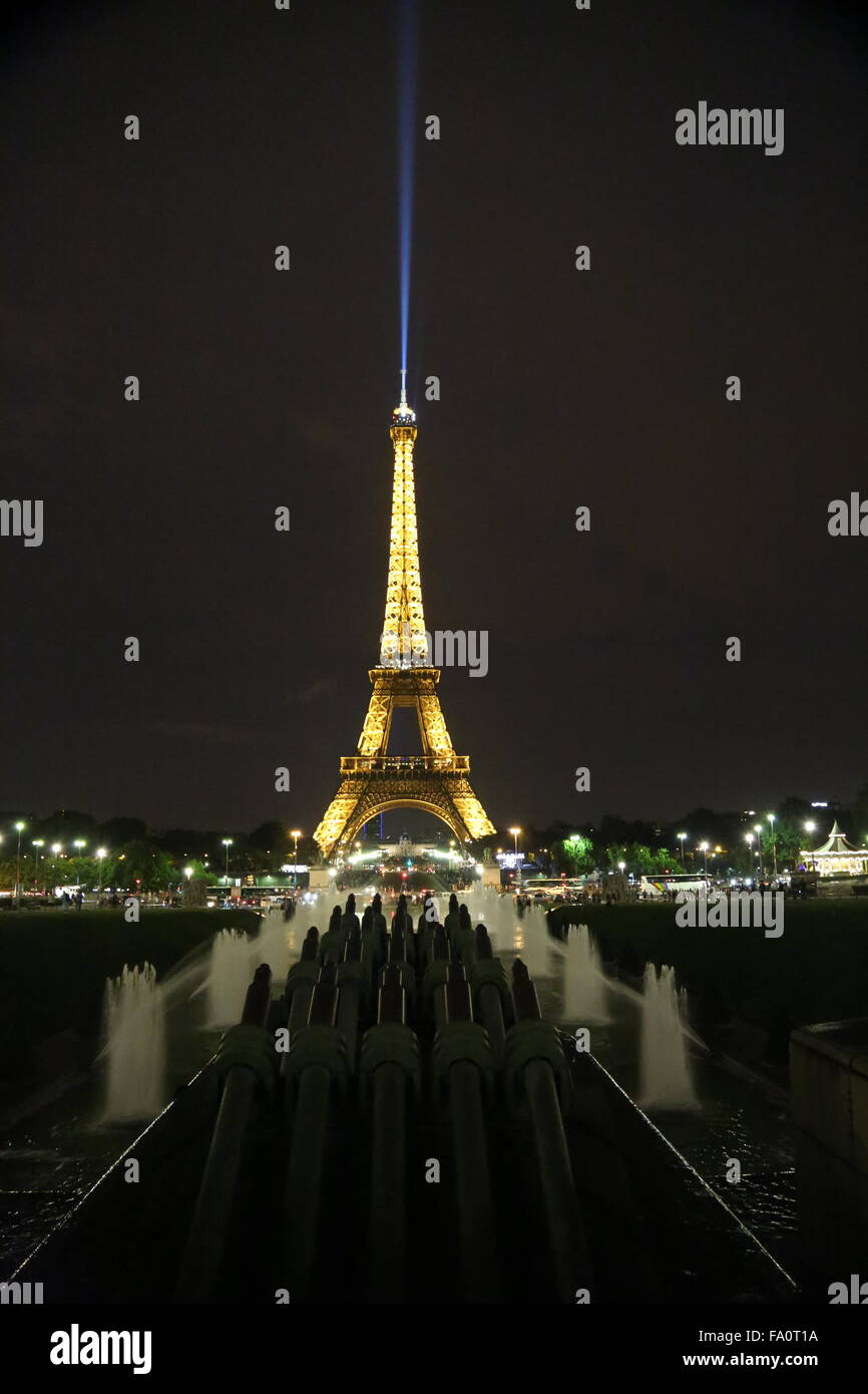 La torre Eiffel di notte con la luce di ricerca sulla punta della torre skyward trainato in background e canoni di acqua... Foto Stock