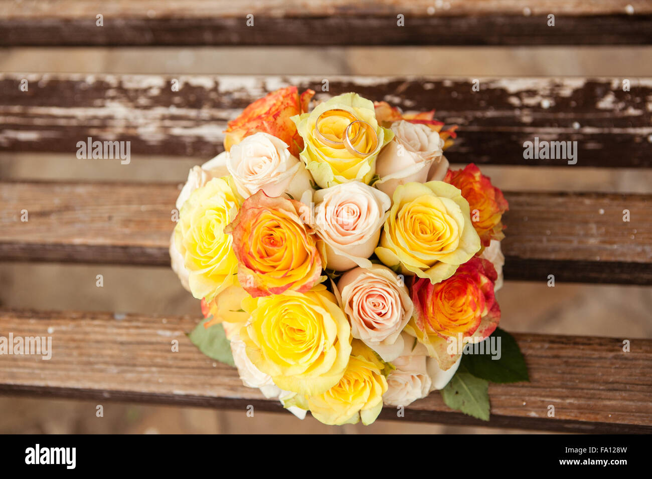 Gli anelli di nozze giacciono su un bouquet di giallo e arancione rose Foto Stock