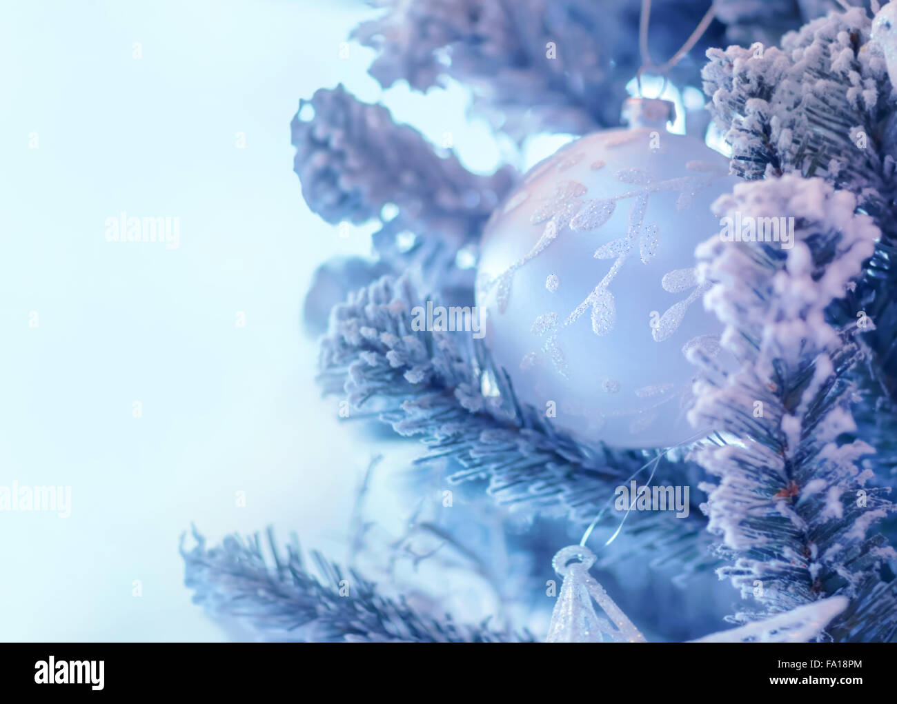 Bellissimo albero di Natale di confine, bianco dolce ninnolo appeso sul ramoscello di pino con neve su Cancella sfondo blu Foto Stock
