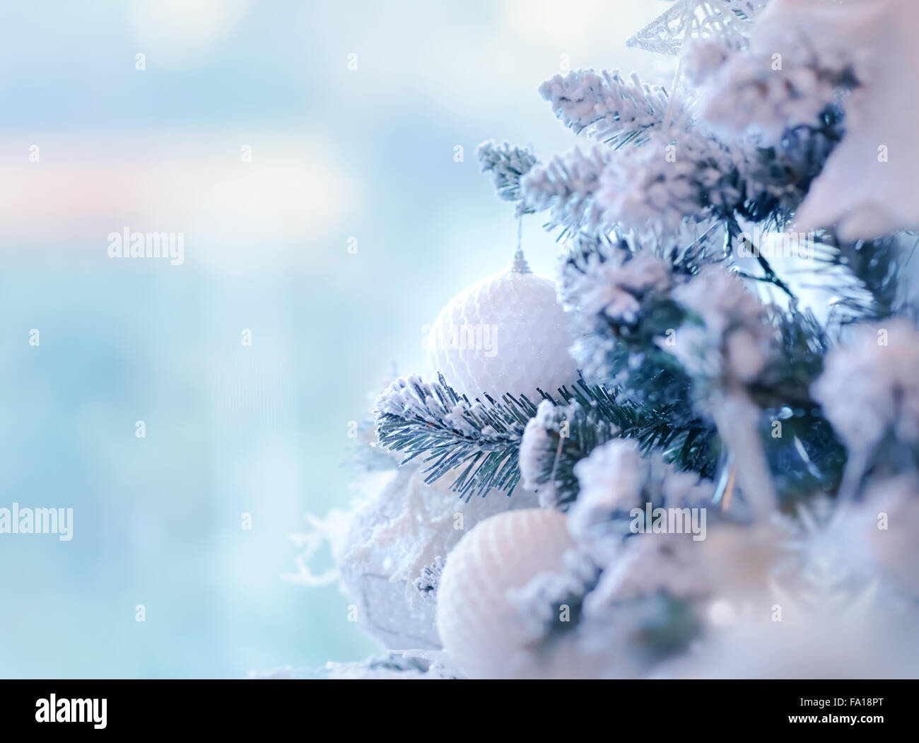 Bellissimo albero di Natale di confine, bianco dolce ninnolo appeso sul ramoscello di pino coperte di neve su sfondo blu Foto Stock