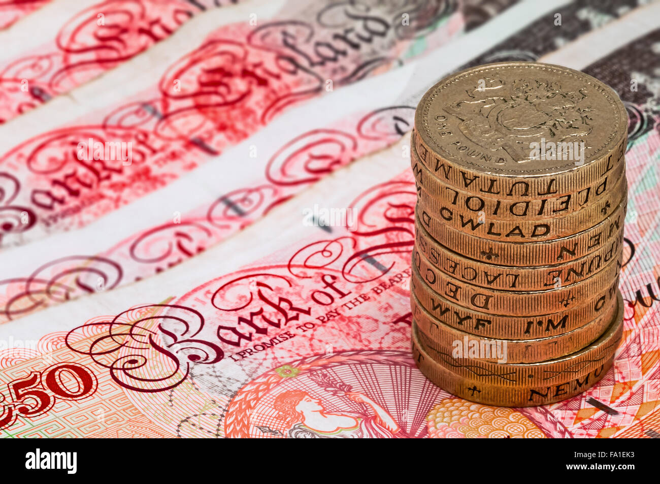 Primo piano vista macro presso la valuta britannica cinquanta pound banconote e la pila di una libbra di monete Foto Stock