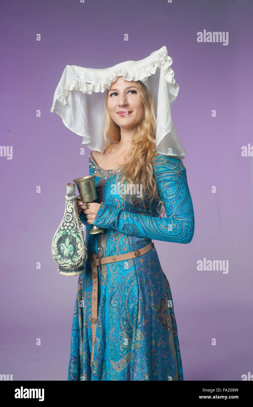 Studio shot della bella ragazza vestita come una nobildonna medievale con un vaso su sfondo viola Foto Stock