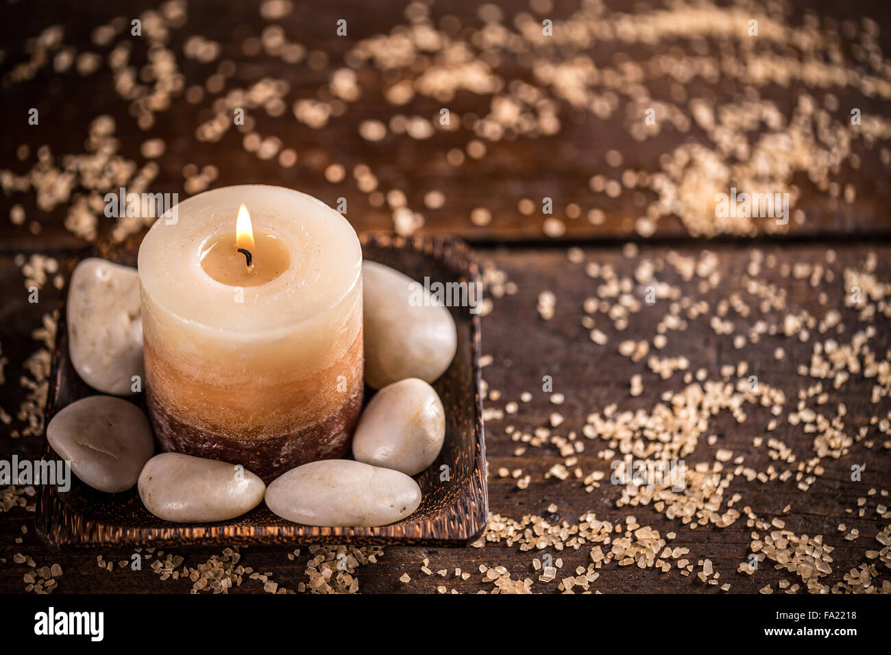 Bella composizione con candela e pietre su sfondo di legno Foto Stock