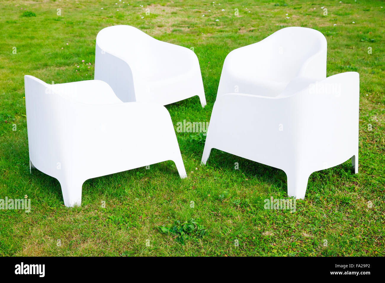 Quattro moderne sedie in plastica bianca stand su fresco verde erba Foto Stock