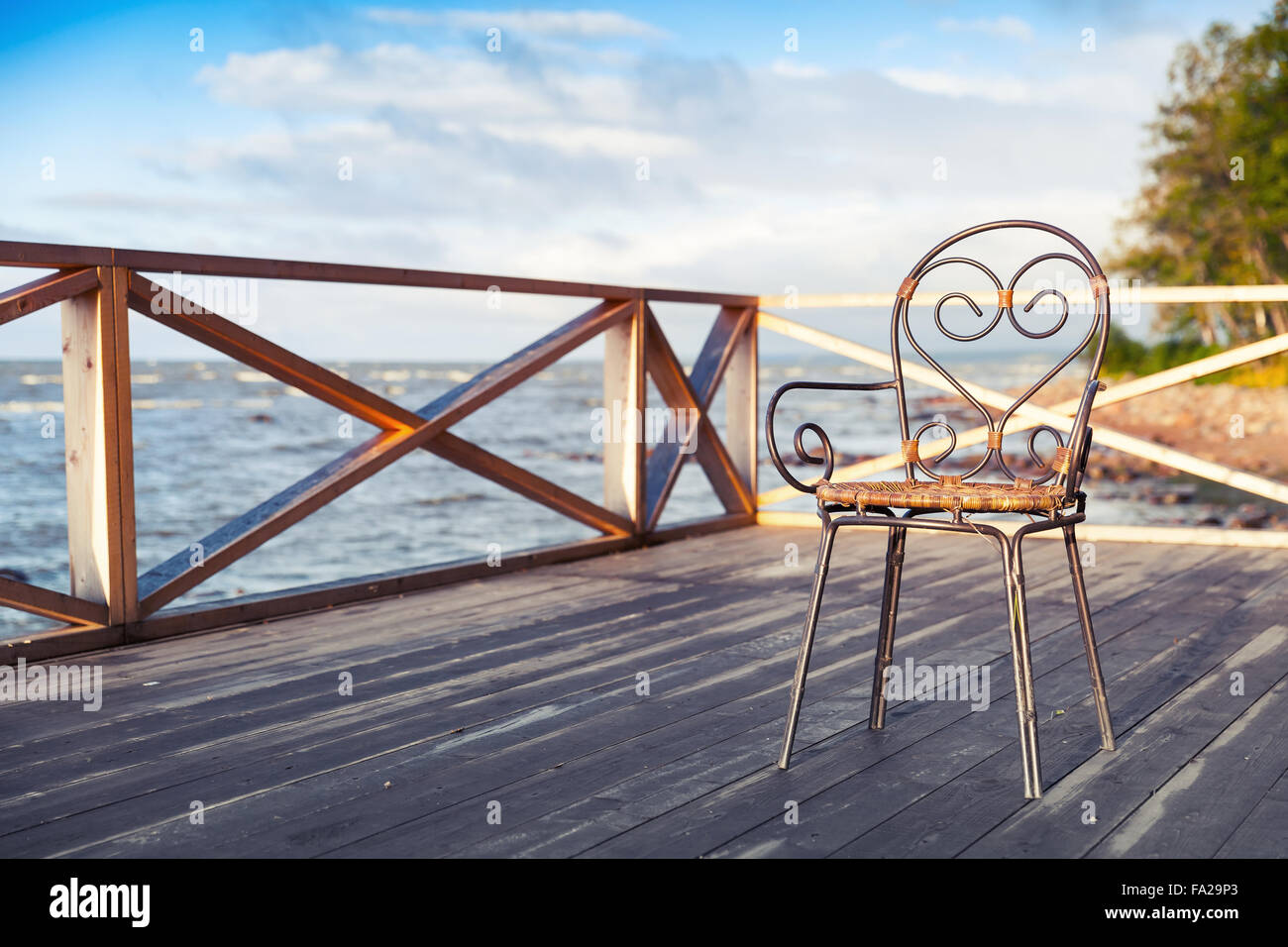 Ferro battuto sedia in piedi sul legno terrazza sul mare Foto Stock